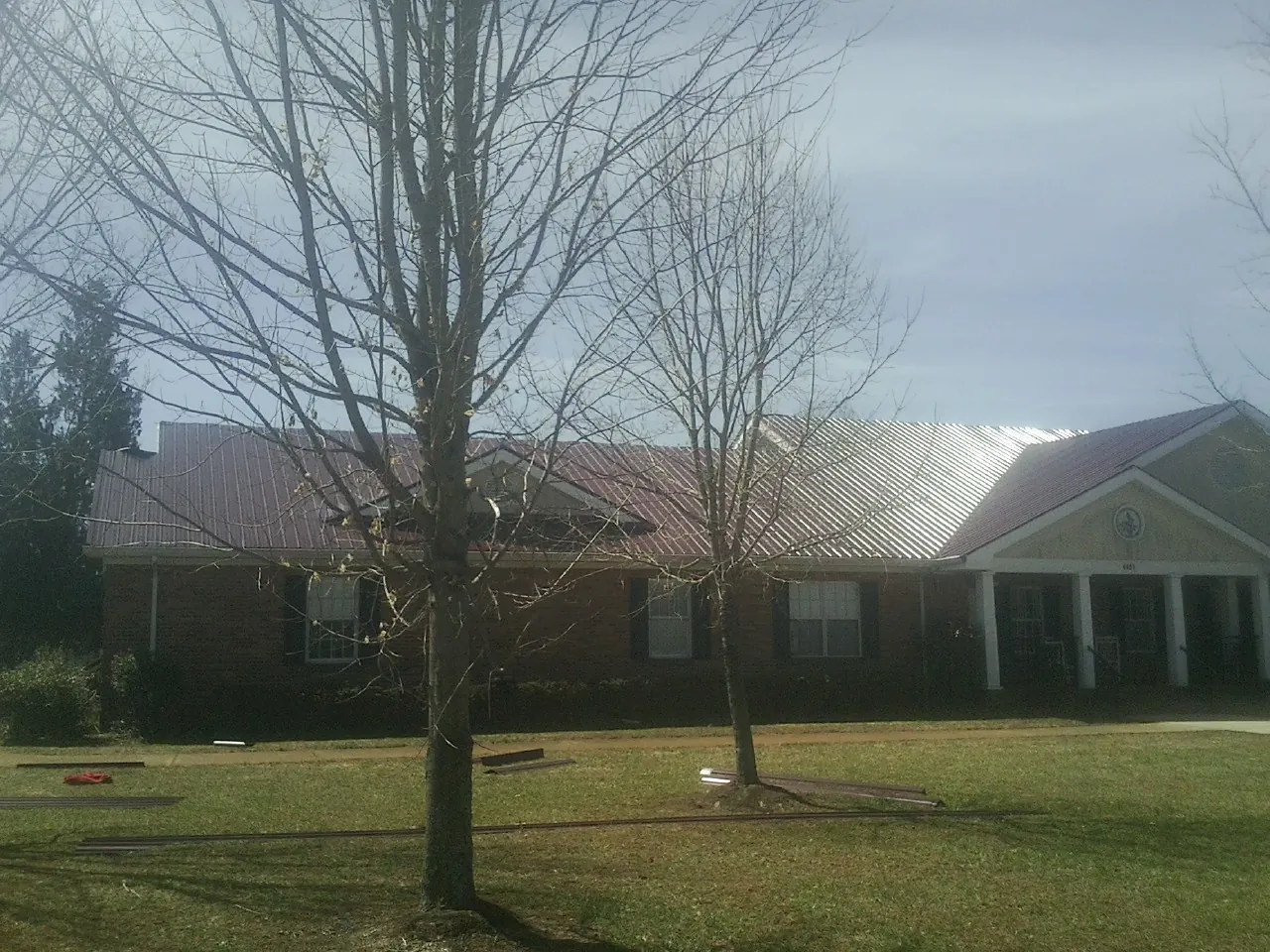 Red metal roof on a brick building seen from the front lawn in Lowell