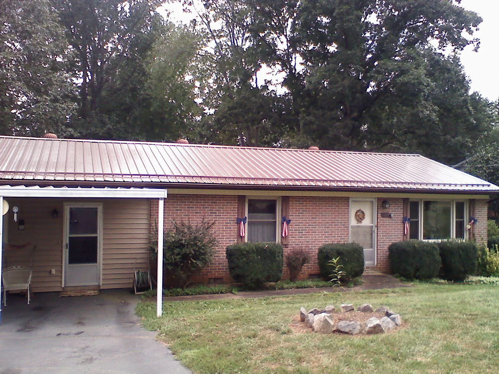 Bronze metal roof and carport on a brick ranch home — Roof Repair work by our crew in Lowell